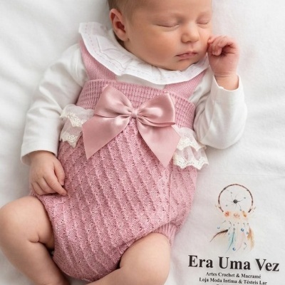 Bebé a dormir vestido com fato de malha rosa com laço e camisola branca numa manta com texto Era Uma Vez