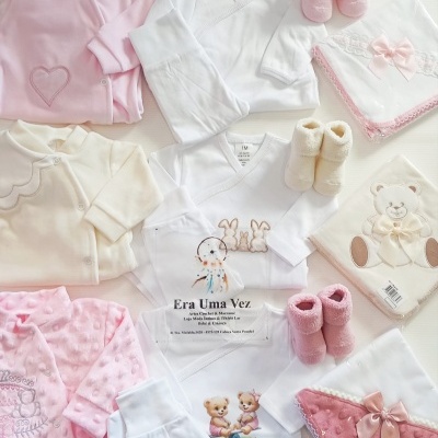 Conjunto de roupa de bebé com macacões, botinhas e toalhas decoradas em rosa, branco e creme