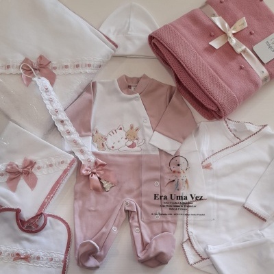 Conjunto de roupas e acessórios de bebé rosa e branco com estampas e detalhes em laço.