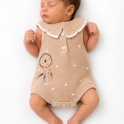 Bebé dormindo vestido com macacão de tricô bege em fundo branco