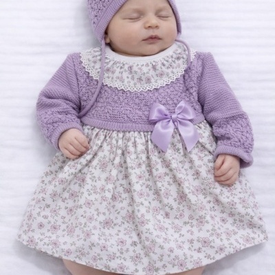 Bebé deitado com roupa lilás de malha e vestido com padrão floral