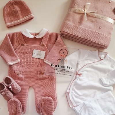 Conjunto de roupa de bebé com macacão, gorro, botins, body branco e manta cor de rosa