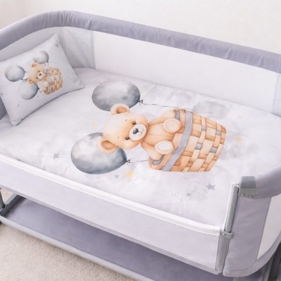 Berço para bebé com roupa de cama branca e estampa de urso em cesto de balão cinzento.