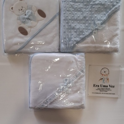 Toalhas de bebé brancas e azul claro com laços azuis e uma placa da loja Era Uma Vez