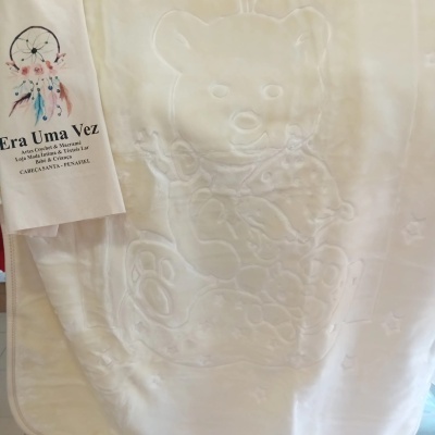 Colcha branca com relevo de ursos e etiqueta com texto e atrapalhador de sonhos colorido