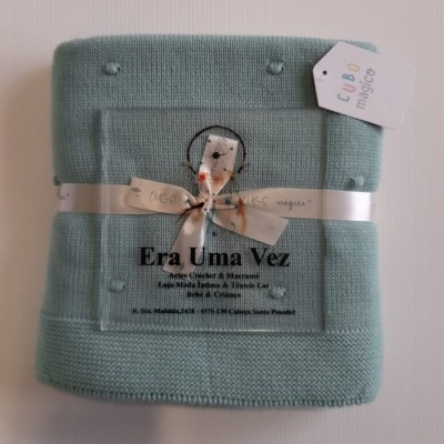 Manta azul tricotada com laço e etiqueta CUBO mágico