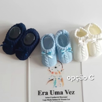 Três pares de sapatinhos de bebê de malha nas cores azul escuro, azul claro e branco com laços