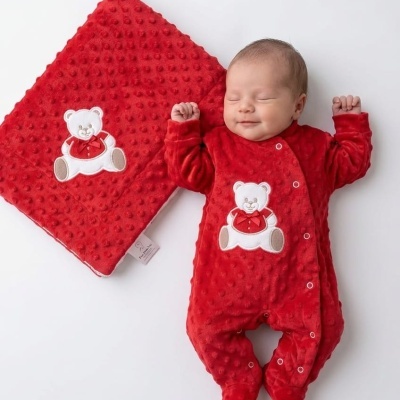 Bebé dormindo vestido com macaquinho vermelho com textura e ursinho, junto a cobertor vermelho com ursinho