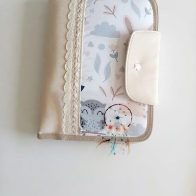 Capa de tecido bege e branco com estampa de coruja, renda, fecho e apanhador de sonhos