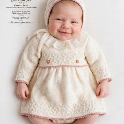 Bebé com roupa de malha creme e gorro, sobre fundo branco.