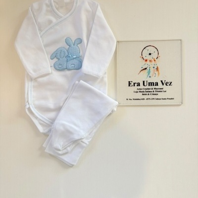 Roupa branca de bebé com bordado azul de coelhos e placa decorativa com apanhador de sonhos e texto