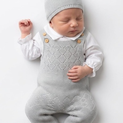 Bebé dormindo com roupa tricotada cinza e camisa branca