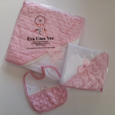 Conjunto para bebé rosa com babete, toalha com capuz e manta, em tecido com textura bolha.