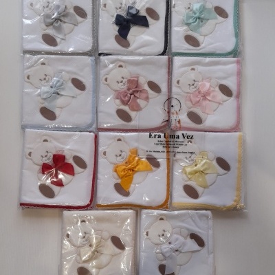 Fraldas de pano para bebés com ursinho e laço colorido embaladas em plástico.