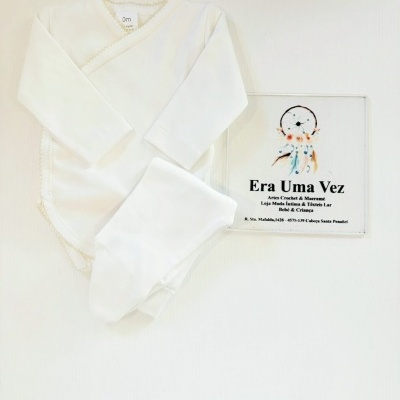 Conjunto de roupa de bebé branca com corpo e calças e placa informativa da loja Era Uma Vez