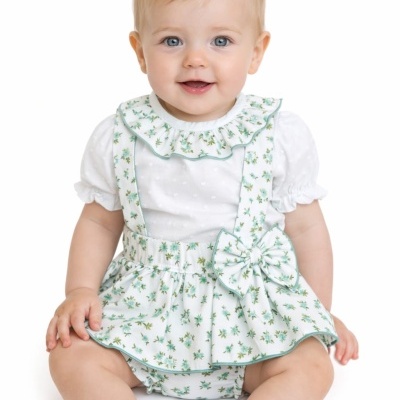 Bebé com vestido branco floral e laço sentada isolada