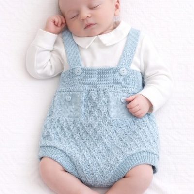 Bebé dormindo com jardineira azul de malha e body branco