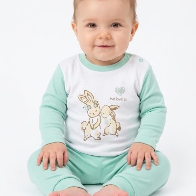 Bebé com pijama com estampa de coelhinhos e texto We love U