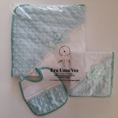 Conjunto de bebé azul claro com textura de bolinhas e detalhes verdes em embalagem com texto