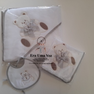 Conjunto de toalha de banho, babete e fraldário de bebé com padrão de ursinho e laço cinza.