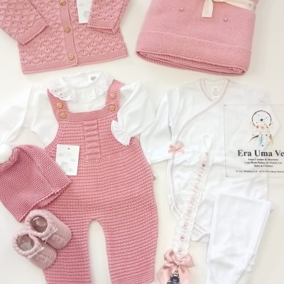 Conjunto roupa bebé rosa e branco com malha, botões de madeira, manta, babygrow e prendedor de chupeta.
