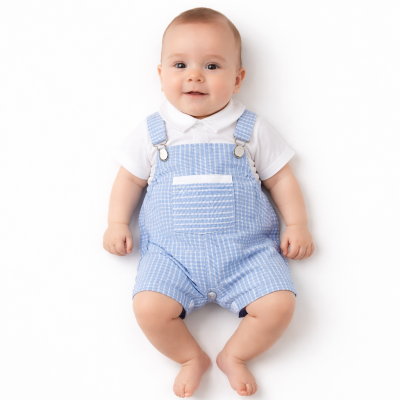 Bebé com jardineira azul e camisa branca sentado