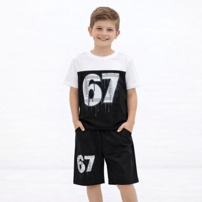 Menino com t-shirt branca e preta e calções pretos com número 67 estampado.
