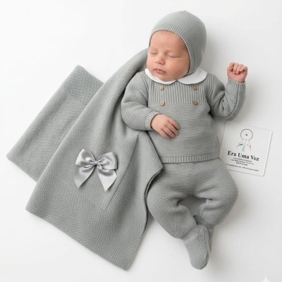 Bebé com roupa e manta cinza de malha, deitado sobre fundo branco