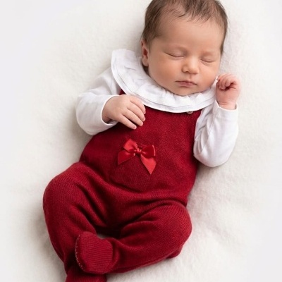 Bebé dormindo com roupa vermelha de malha e camiseta branca