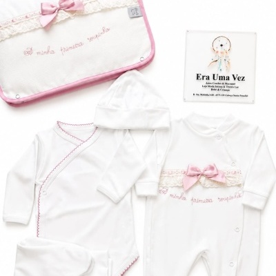 Conjunto de roupa de bebé branca com laço rosa e bolsa com frase bordada.