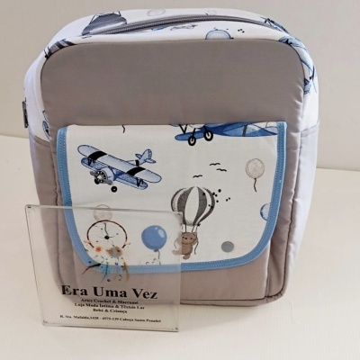 Mochila cinza com bolso estampado de aviões e balões, com placa acrílica com texto Era Uma Vez