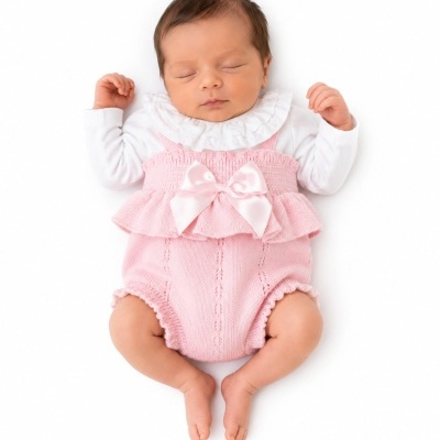 Bebé vestido com roupa branca e rosa em fundo branco