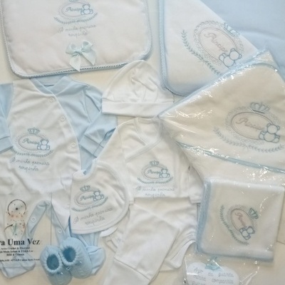 Conjunto azul e branco para bebé com bodies, babete, gorro, mantas e toalhas bordadas, sapatinhos e coração decorativo.