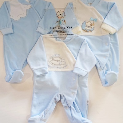 Três pijamas de bebé azuis e brancos com desenhos bordados e botões de pressão, com placa transparente no centro com texto da loja