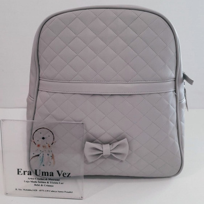 Mochila cinzenta com padrão em losangos e laço decorativo.