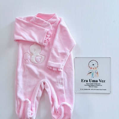 Pijama rosa de veludo para bebé com desenhos de patinhos e placa com texto relacionada sob fundo branco