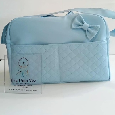 Mala azul clara com bolso acolchoado e laço em fundo branco