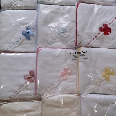 Toalhas brancas com bordados e laços coloridos embaladas em plástico