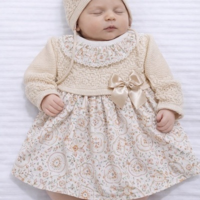 Bebé vestido com conjunto de malha creme e vestido branco floral com laço creme