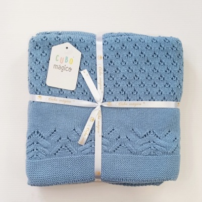 Manta de malha azul clara com padrão decorativo embalada com fita e etiqueta