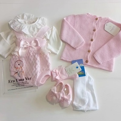 Conjunto de roupa de bebé rosa e branco com cardigan, macacão de crochet, sapatinhos e acessórios