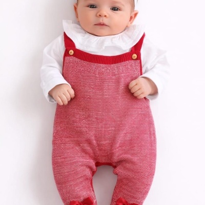 Bebé com jardineira vermelha e branca, blusa branca e faixa de cabelo