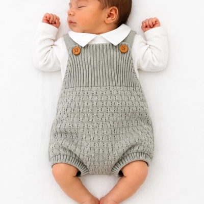 Bebé a dormir com macacão de malha cinzento e camisa branca