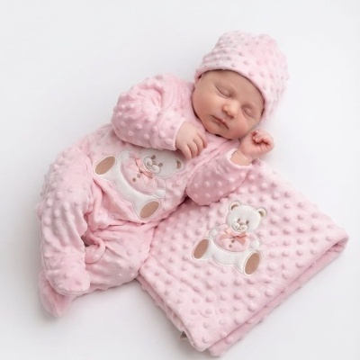 Bebé vestido de rosa com conjunto de macacão, gorro e manta com ursinho bordado.