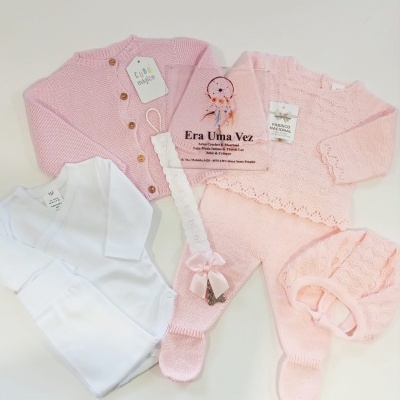 Conjunto de roupa de bebé em branco e rosa com etiquetas e detalhes rendados.