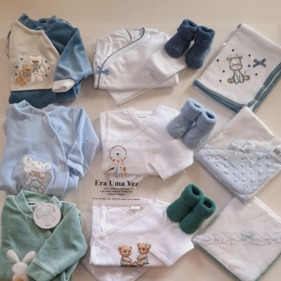 Roupas e acessórios de bebé em azul, branco e verde com bordados de animais e etiquetas visíveis