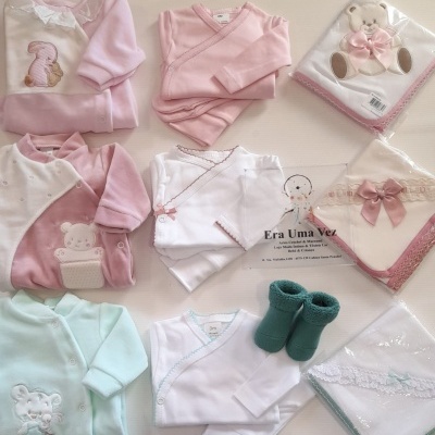 Conjunto de roupa e acessórios para bebé em tons pastel com bordados e laços