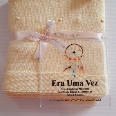 Manta amarela clara com pompons e etiqueta de loja Era Uma Vez