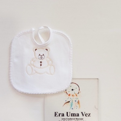 Babete branco com urso bordado e cartão promocional de loja