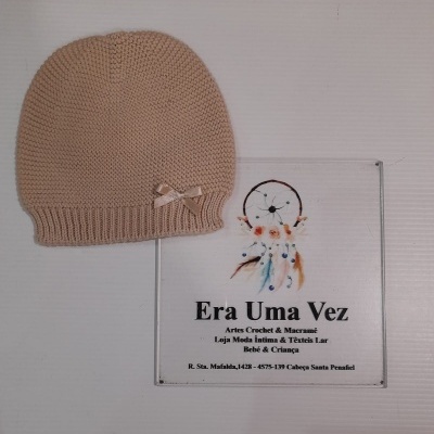 Gorro de malha bege com laço e cartaz de loja artesanal